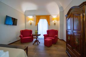 a hotel room with two red chairs and a bed at Hotel La Plumeria in Cefalù