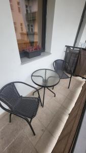 three chairs and a glass table on a balcony at Downtown Boho Botanico in Brno