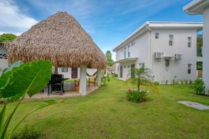 a grass roofed gazebo in the yard of a house at Bambu Beach Haus Coronado in Las Lajas