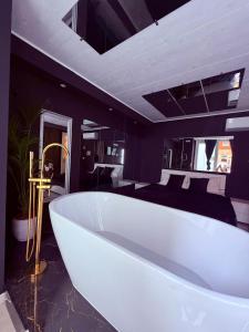 a large white bath tub in a room with a bed at Ama Suite Romantic Spa in Bologna