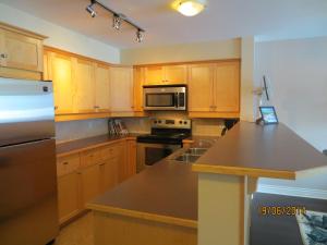 a kitchen with wooden cabinets and stainless steel appliances at Kaslo Bay Condominium in Kaslo