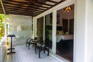 a porch with a table and chairs and a bed at Zara Beach Resort Koh Samui in Lamai