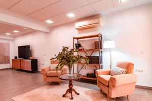 a living room with two chairs and a table and a tv at EDomus Medellin 1485 Suites in Don Benito