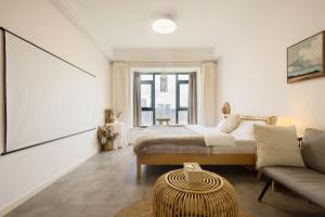 a bedroom with a bed and a couch and a window at ROLA&RICCI Hotel Chengdu East Branch in Chengdu