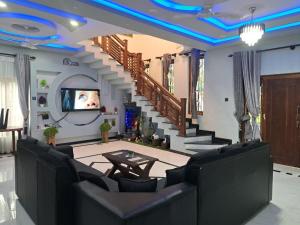 a living room with couches and a tv and stairs at Asmi Villa in Jaffna