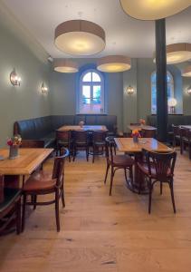 a dining room with wooden tables and chairs at 3sine - Ihr besonderer Gasthof im Bahnhof Deisenhofen in Oberhaching
