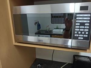 a microwave with a person taking a picture of a kitchen at Pennington Holiday Cottages in Pennington