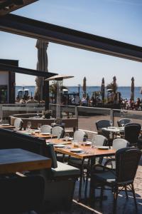 a restaurant with wooden tables and chairs and the ocean at Hotel Bella Ciao in Harderwijk