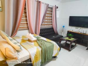 a bedroom with a bed and a couch and a television at Sugarland Urban Nook in Bacolod