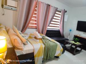 a bedroom with a bed and a chair and a window at Sugarland Urban Nook in Bacolod