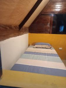 a bed in a room with yellow and blue stripes at Lucmabamba Cabaña de los Duendes in Sahuayacu +17 photos