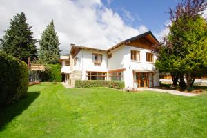 a large white house with a green yard at Hostería Carelhue in San Carlos de Bariloche