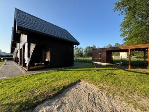 a black house with a gambrel roof on a yard at Morze Lubiatowo in Lubiatowo
