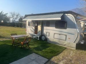 a white caravan parked in a yard with a table at Camping Alex in Cadenazzo