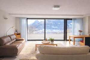 a living room with a couch and a large window at Maison D'Hortense chalet le Chamois in Hérémence