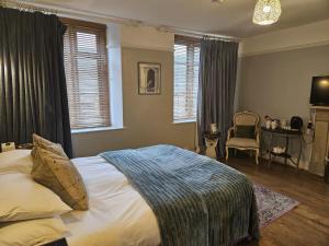 a bedroom with a bed and a chair and windows at Cotswold Gardens Bed and Breakfast in Stow on the Wold