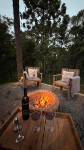 a wooden table with wine glasses and a fire pit at Cabanas Green Valley in Monte Verde