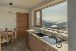 a kitchen with a sink and a large window at Nest Love, Bedollo Ospitar in Bedollo