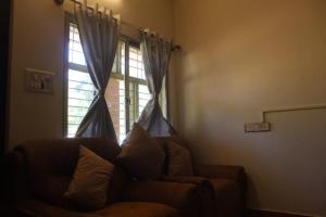 a living room with a couch and a window at Aroha Farm Stay in Yelagiri
