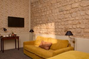a living room with a yellow couch and a tv at Hotel des Orfèvres in Paris