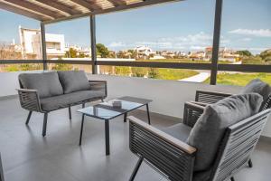 a living room with chairs and a table and windows at Azure Harmony Pool Villa by SEM in Áyios Spirídhon