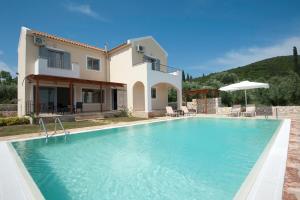 a villa with a swimming pool in front of a house at Villa Harmony in Karavomylos