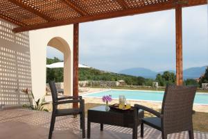 a patio with a table and chairs and a pool at Villa Harmony in Karavomylos +1 photo