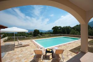 a pool with chairs and a table and an umbrella at Villa Harmony in Karavomylos