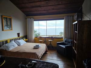 a bedroom with a bed and a chair and a window at Chales Quinteto de Cores in Lavras Novas
