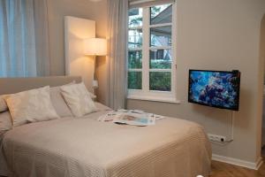 a bedroom with a bed and a tv on a wall at Studio-Apartment Piccolino 26, Timmendorfer Strand- Strandkorb inklusive & privaten Zugang zur Ostsee in Timmendorfer Strand