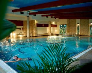 a man swimming in a large swimming pool at Artis Dom Gościnny in Zamość