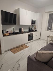 a kitchen with white cabinets and a tv on the wall at Delizioso bilocale Paolo in Alassio