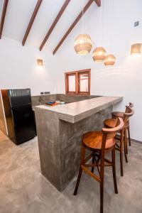 a kitchen with a counter and two stools at Turtle Bay Cottage in Kosgoda