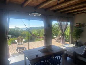 a living room with a table and a large window at Casa Morro da Borússia in Osório +43 photos