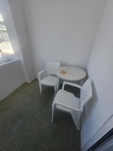 a small table and two white chairs in a room at Romeu in Quarteira