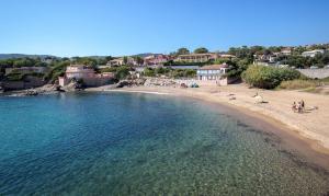 a beach with people sitting on the sand and the water at Monplaisir in Fréjus