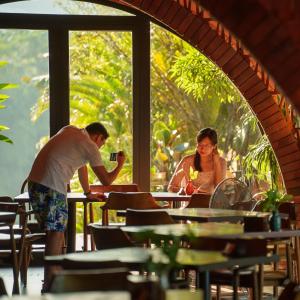 a man taking a picture of a woman sitting at a table at Maida Lodge in Hòa Bình