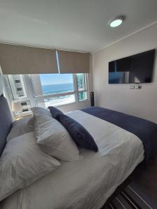 a bedroom with a bed with pillows and a flat screen tv at Apartment in Playa Brava Ocean View & SmartLock in Iquique