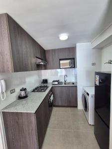 a kitchen with wooden cabinets and a black refrigerator at Apartment in Playa Brava Ocean View & SmartLock in Iquique