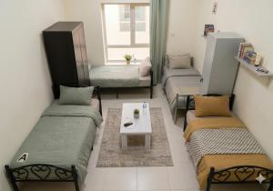 a room with three beds and a table in it at ALEX Hostel - Bed in a shared room - H101 in Sharjah