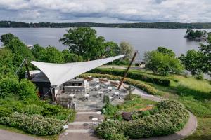 a garden with a white tent in front of a lake at Rönneberga in Lidingö