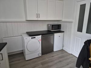 a kitchen with a washing machine and a microwave at Double rooms in Crosby