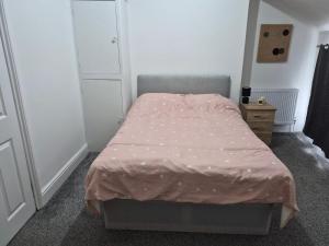 a small bedroom with a bed with a pink comforter at Double rooms in Crosby +4 photos