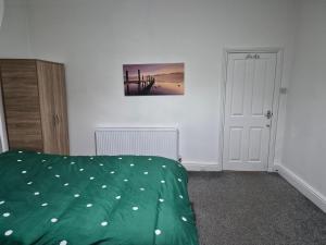 a bedroom with a bed with a green comforter at Double rooms in Crosby