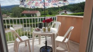 a table and chairs on a balcony with an umbrella at Aux 4 Saisons in Tabre