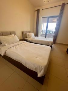 two beds in a hotel room with a window at Samarah EP 04 full Sea View and poll access prime location with big terrace, in Sowayma