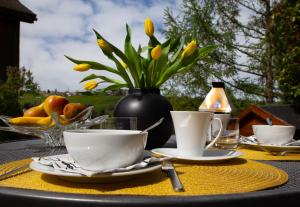 a table with two cups and a vase with yellow flowers at Ursulas BnB Hemberg View in Hemberg