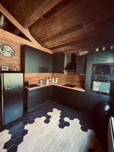 a kitchen with blue cabinets and a black refrigerator at Auvers Wood lodge in Auvers-sur-Oise