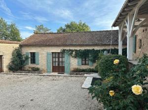 a stone house with a blue door and yellow roses at SOLASI - Gîte et Chambres D'hôtes in Blanquefort-sur-Briolance