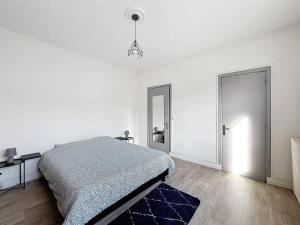 a white bedroom with a bed and a blue rug at L'Hyper Centre - Dunkerque in Dunkerque
